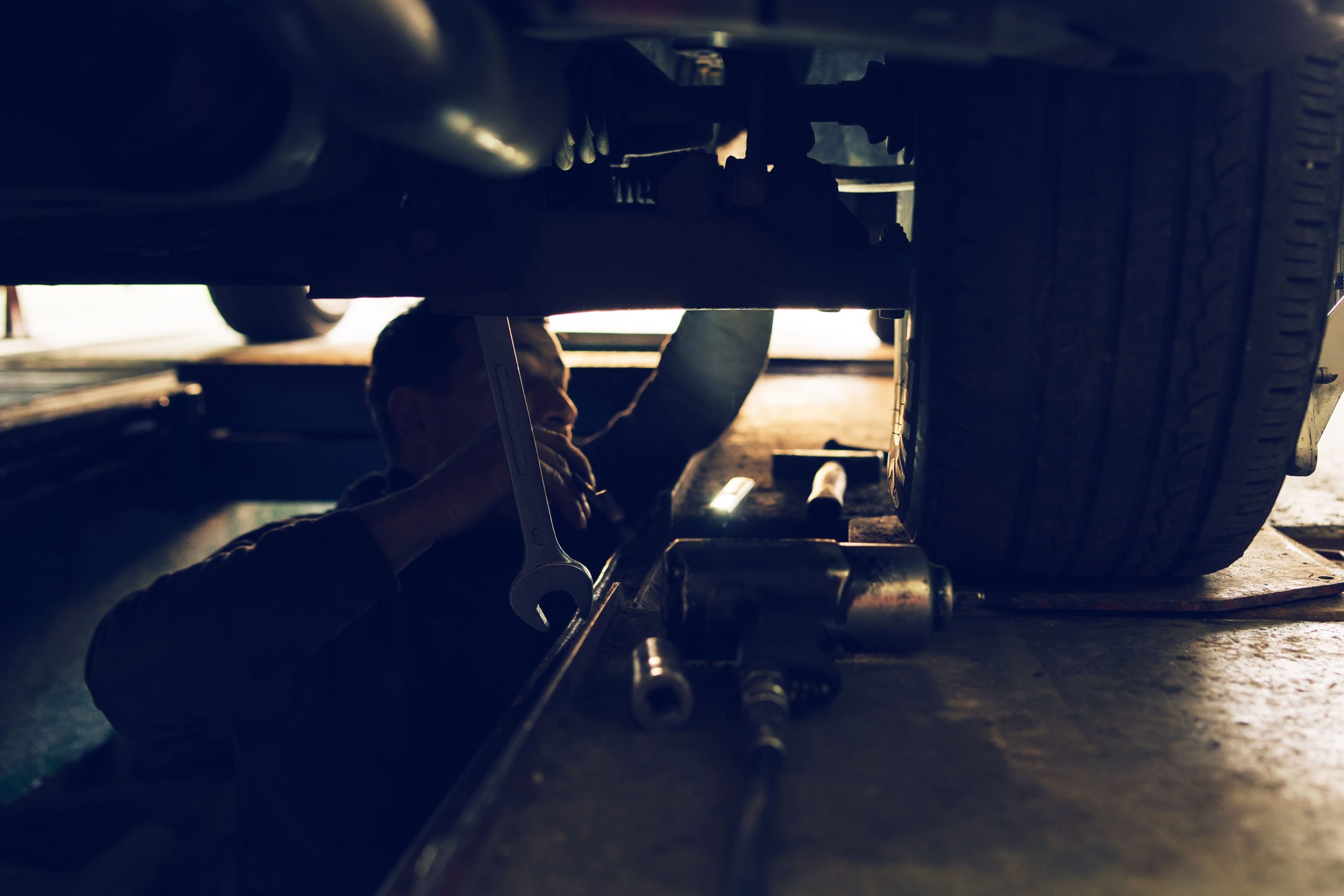 A mechanic with tools positioned underneath a truck, repairing its airbrake systems