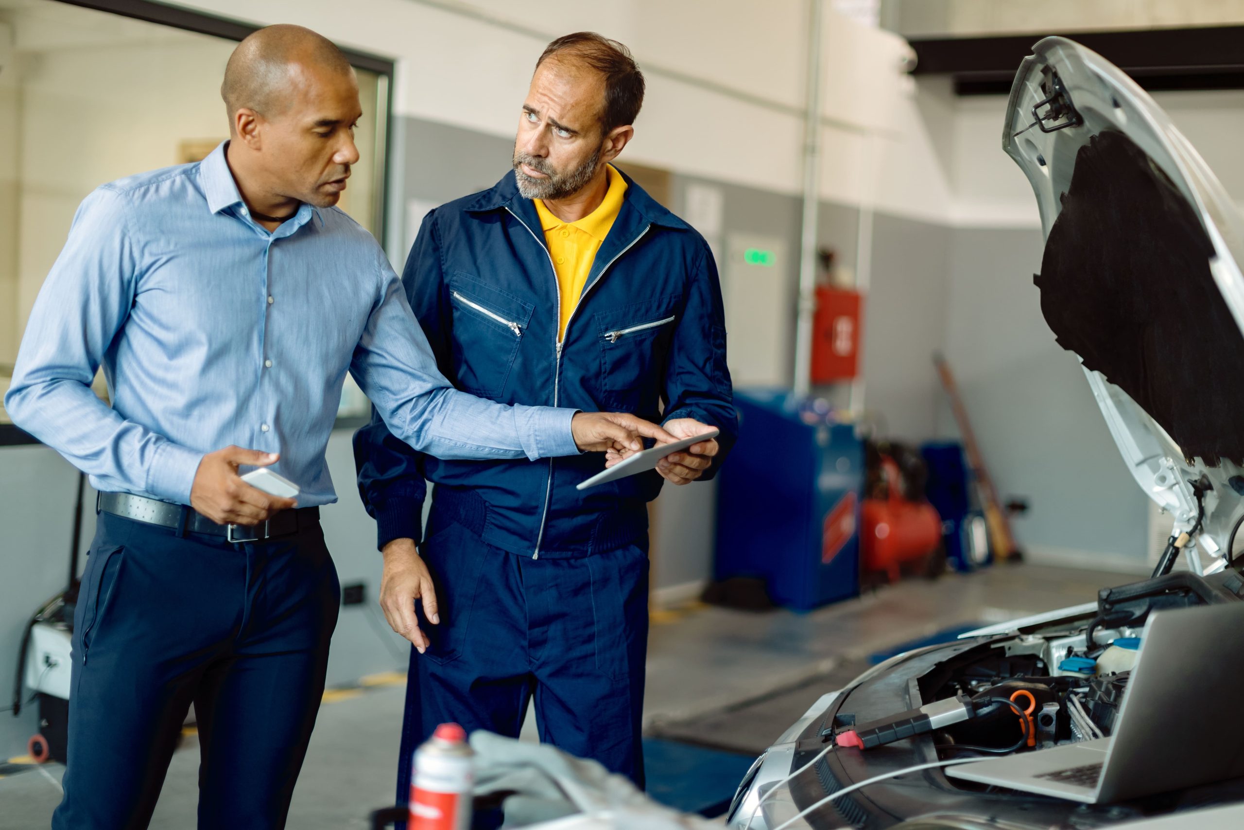 A professional man discussing his brake cleaning service in a workshop with a mechanic