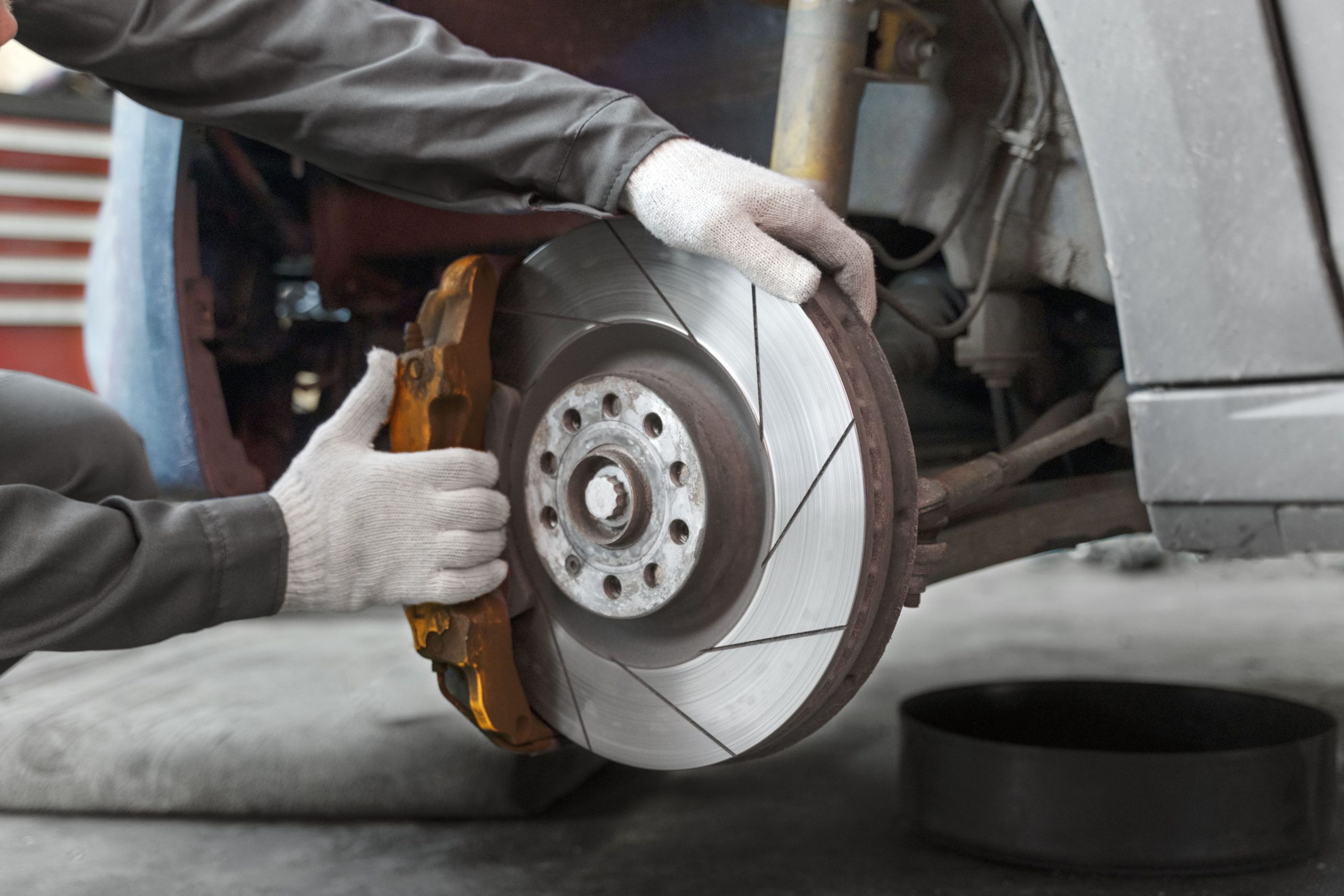 A mechanic wearing white gloves and completing a brakes shoes relining service